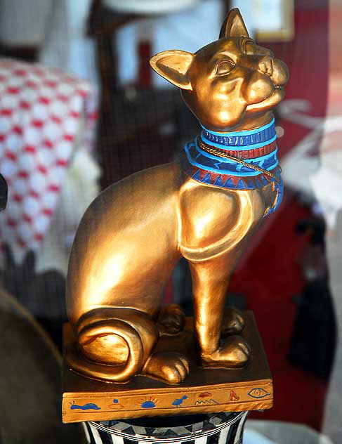 In the window of a gift shop across the street from the Egyptian Theater on Hollywood Boulevard, a gold cat with a blue collar
