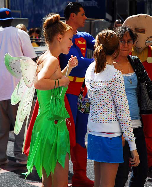 Tinkerbelle impersonator with tourists and other impersonators, on Hollywood Boulevard