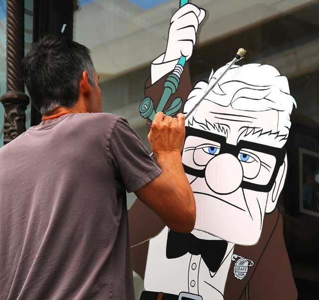 Artist painting figure on the window of the Disney Store, Hollywood Boulevard