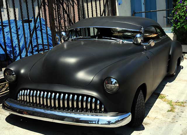 Highly customized flat-black chopped and channeled '51 Mercury parked at a body shop next to a tattoo parlor on Melrose Avenue a few feet east of Cahuenga Boulevard, just south of Hollywood 