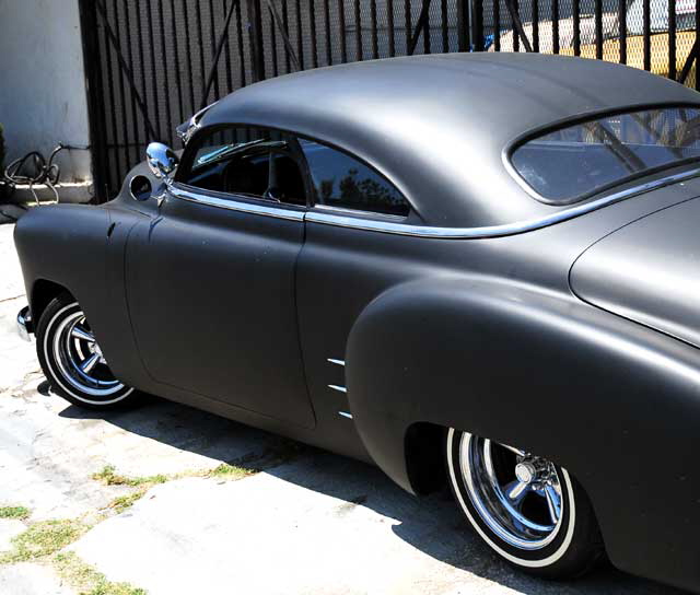 Highly customized flat-black chopped and channeled '51 Mercury parked at a body shop next to a tattoo parlor on Melrose Avenue a few feet east of Cahuenga Boulevard, just south of Hollywood 