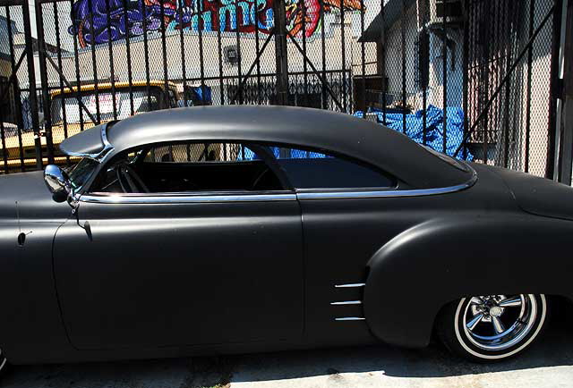 Highly customized flat-black chopped and channeled '51 Mercury parked at a body shop next to a tattoo parlor on Melrose Avenue a few feet east of Cahuenga Boulevard, just south of Hollywood 