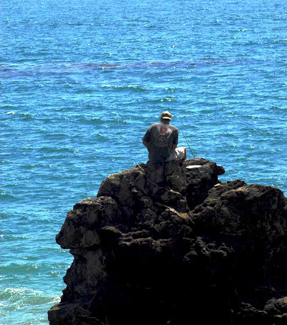 Man fishing from large rock just off the beach in Malibu, near Topanga Canyon 