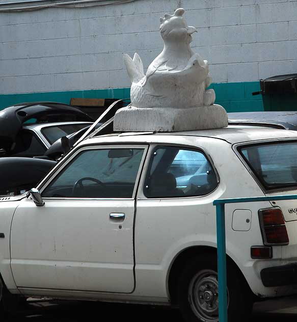 Santa Monica Boulevard, a Honda in the shop - large stone chicken on the roof 