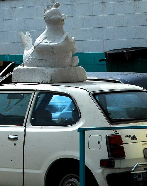 Santa Monica Boulevard, a Honda in the shop - large stone chicken on the roof 