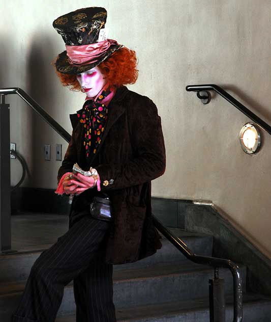 A Mat Hatter impersonator stops to count his tips in the stairwell of Grauman's Chinese Theater