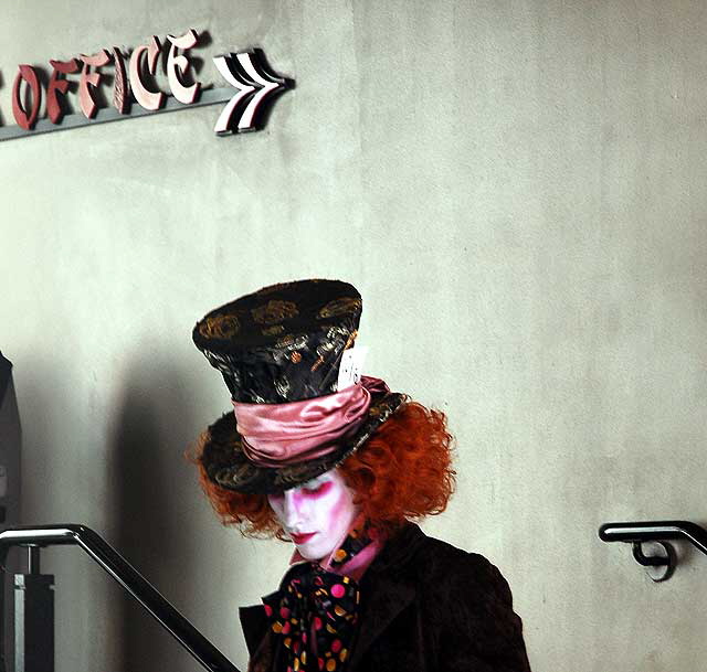 A Mat Hatter impersonator stops to count his tips in the stairwell of Grauman's Chinese Theater