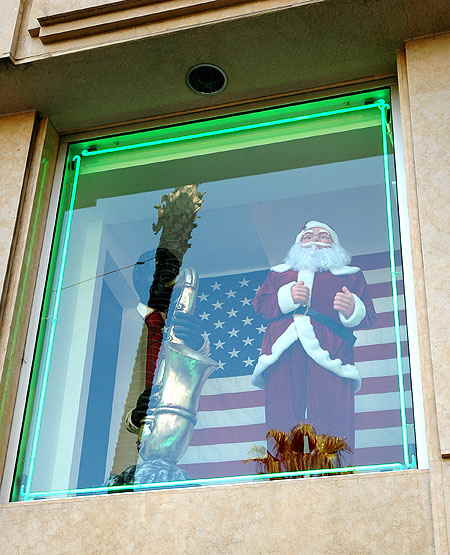 Across the street at Hollywood and Vine, at Iguana Vintage Clothing, an all American Santa - green neon, the flag, the jazzman and the reflection of a palm tree in the glass.