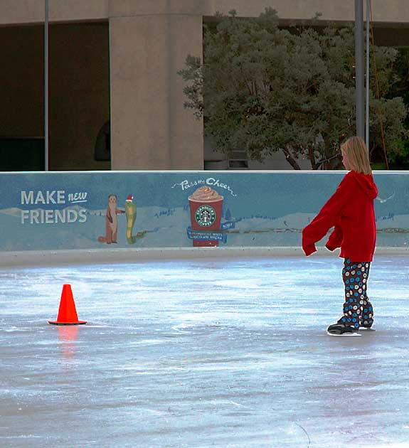 A young ice-skater and her short orange friend at the public ice rink in Santa Monica, Arizona at Fourth