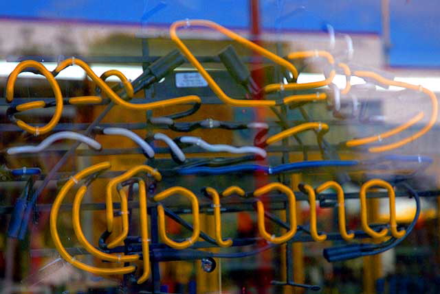 Neon escapist messages in a liquor store window on Pico, near the freeway