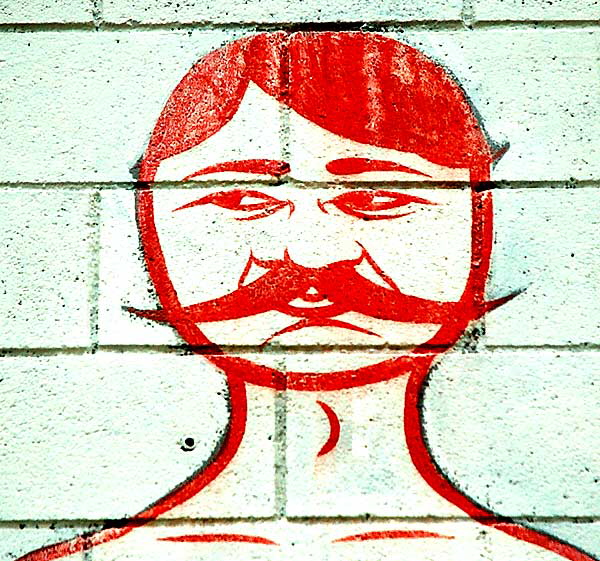 A naked man with a mustache on a wall on La Cienega near the freeway