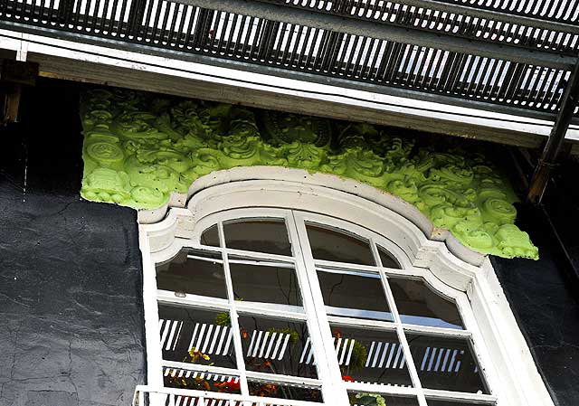 Black wall with white window, green ornamentation, all under a billboard - Melrose Avenue