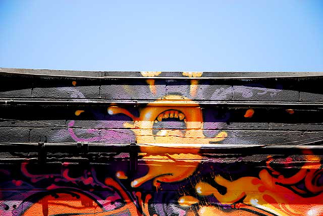 Orange face on black wall, alley graffiti, Melrose Avenue