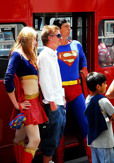 Tourist posing for picture with Superman and Supergirl impersonators, Hollywood Boulevard