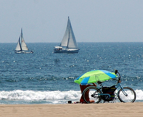 Blond on the sand with bicycle, sailboats in background, Venice Beach