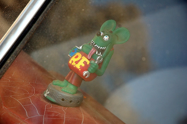 Rat Fink on dashboard of a 1953 Mercury coupe, in flat black primer with the flames at the wheel wells, chopped and channeled and done up in the manner of Ed "Big Daddy" Roth