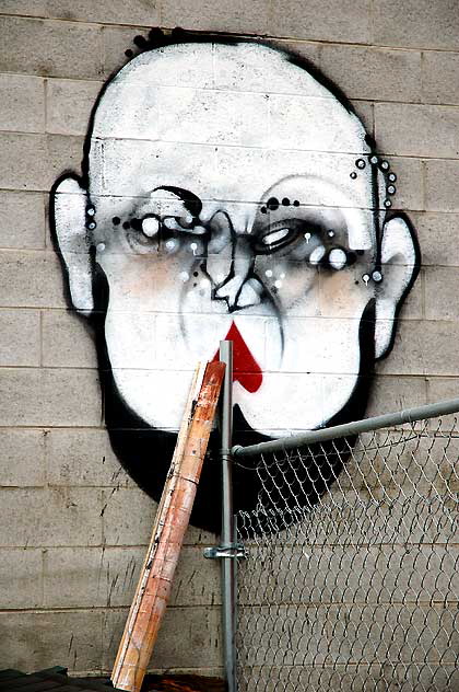 Surreal clown face on concrete block wall, alley behind Hollywood Boulev