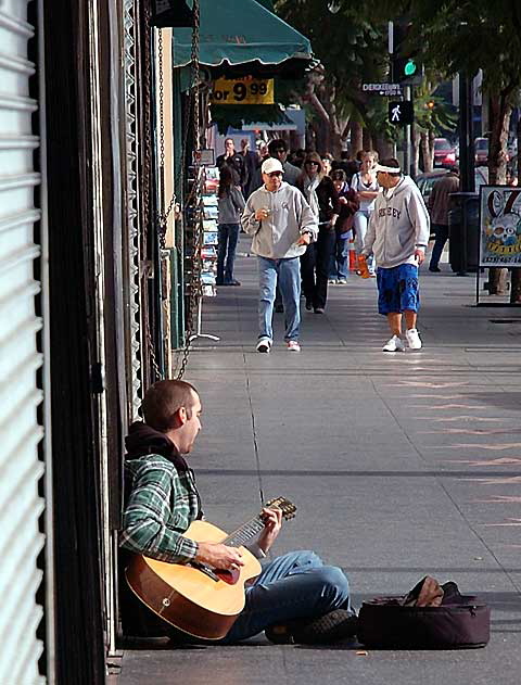 Street musician playing acoustic guitar on the Hollywood Walk of Fame